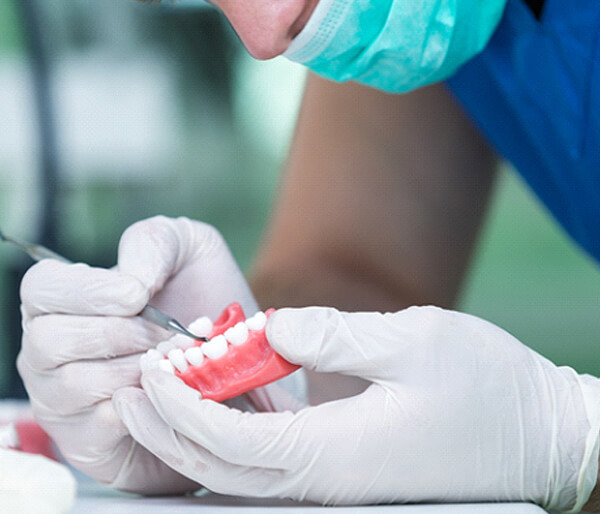 Dental laboratory technician with gloved hands carefully working on dentures