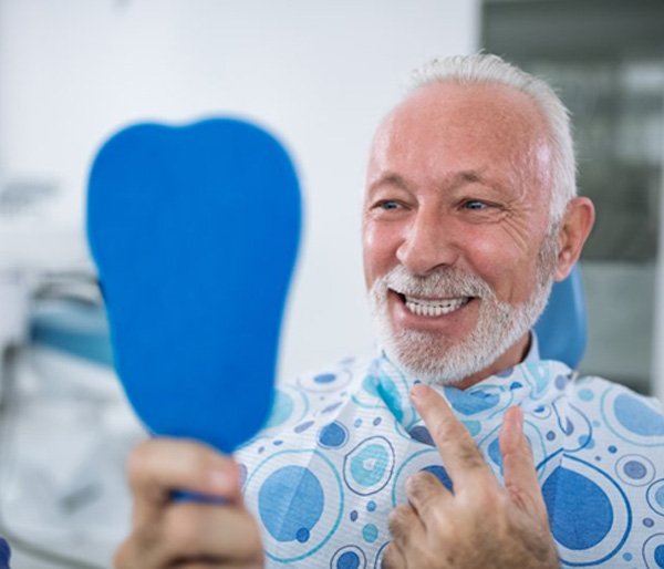 senior man admiring his new smile with dental implants 