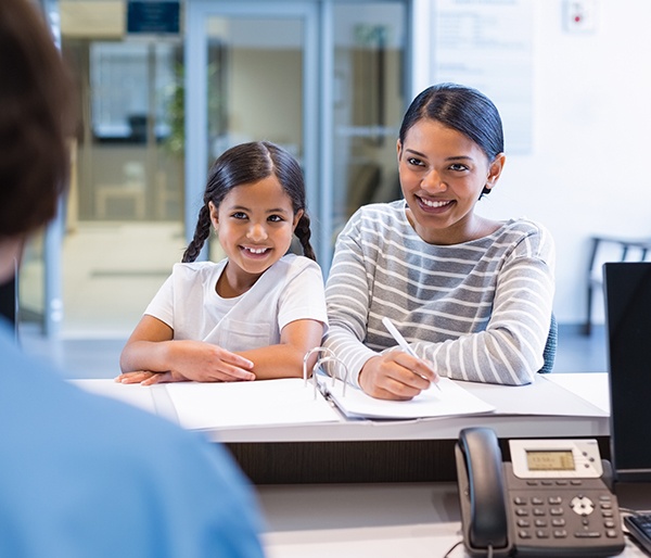 Mother and daughter checking in at dental office reception desk