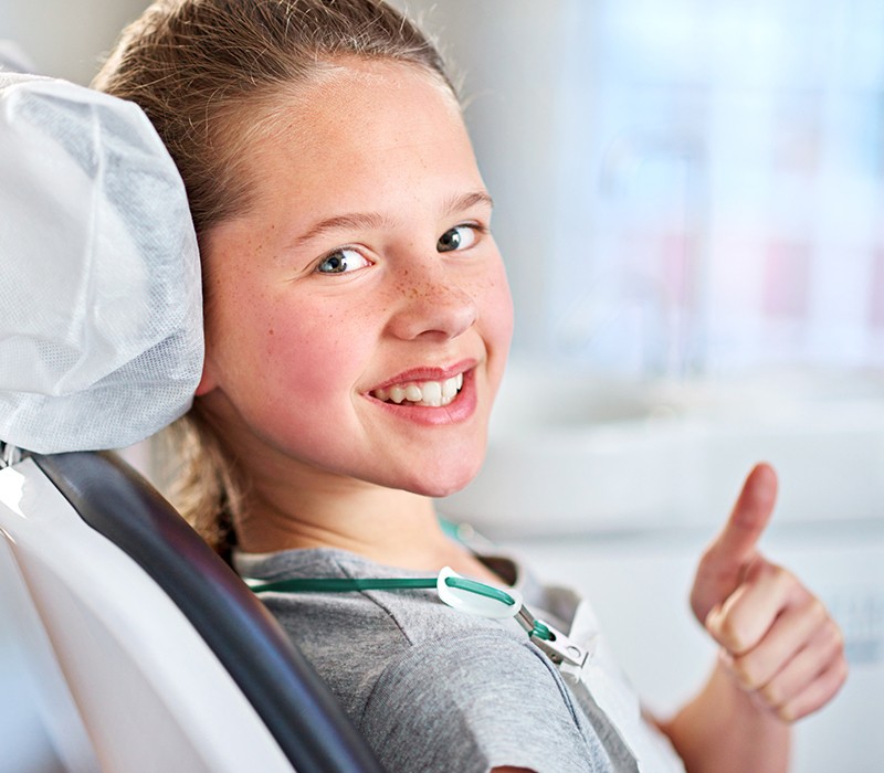 Little girl giving thumbs up during children's dentistry visit