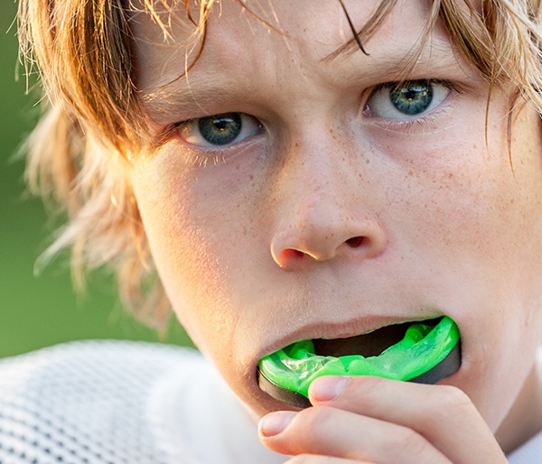 Teen boy placing green athletic mouthguard