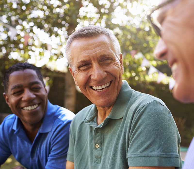 Three friends with dentures laughing together outdoors