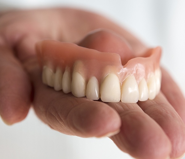 Hand holding a full denture