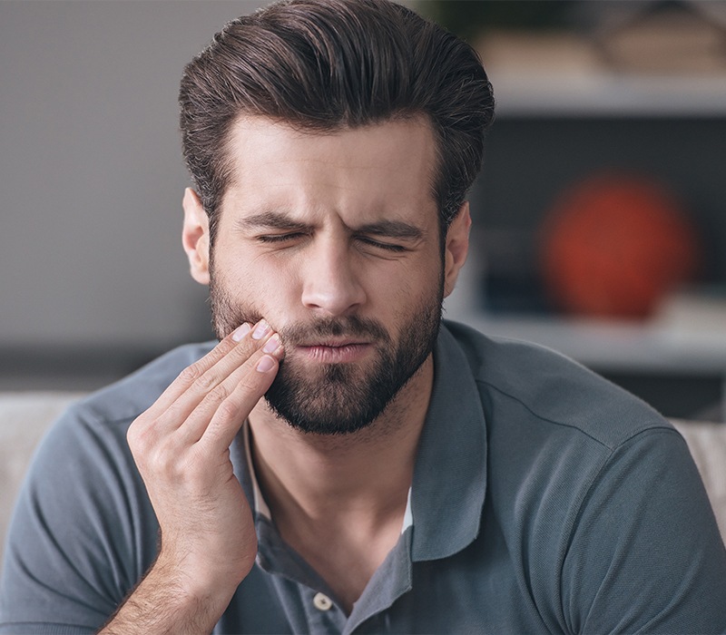 Man in need of emergency dentistry holding jaw