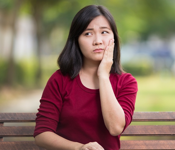 Young woman in need of emergency dentistry holding jaw