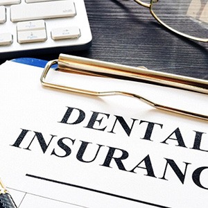 Dental insurance claim form on clipboard, next to glasses