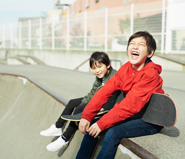 Two kids holding skateboards laughing