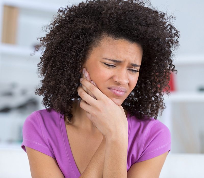 Woman in need of tooth extraction holding cheek