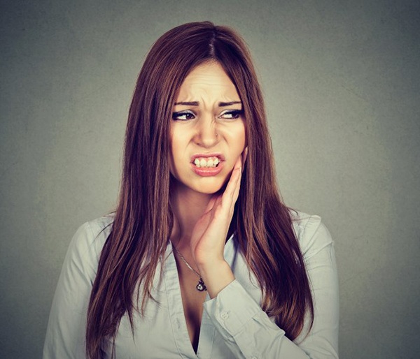 pained woman wonders if she needs a tooth extraction in Flint