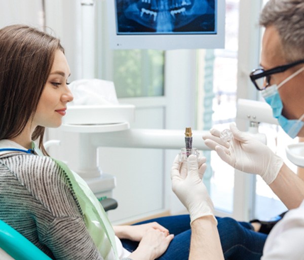 dentist showing a dental implant to a patient 