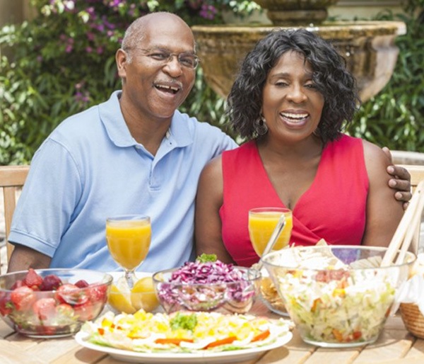 man and woman sitting at a table with various foods  