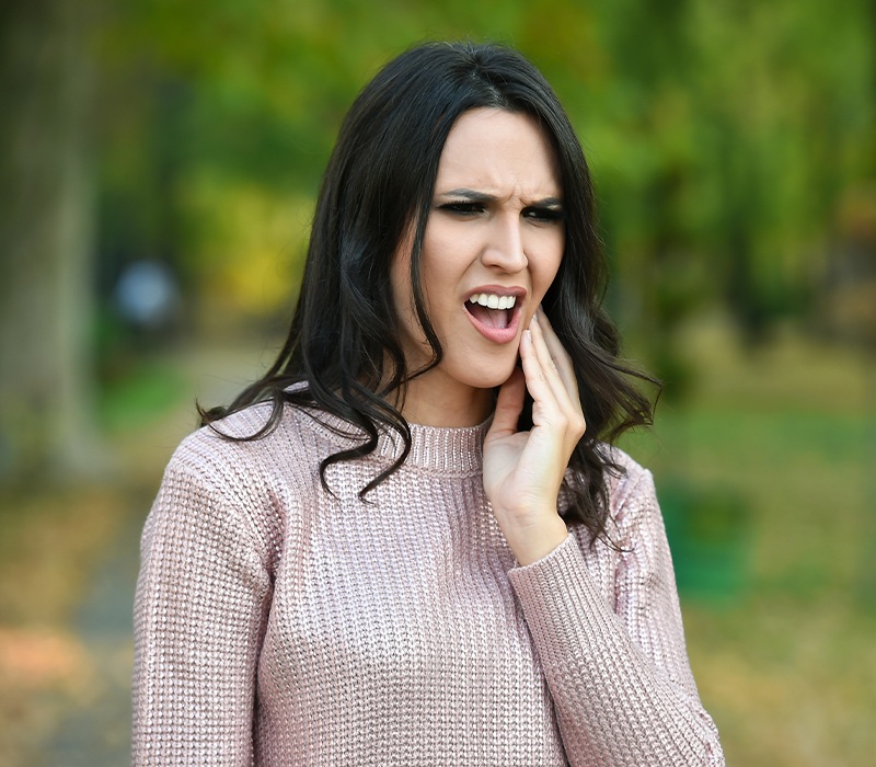 Woman in need of root canal therapy holding jaw in pain