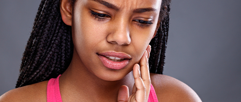 Woman in need of emergency dentistry holding cheek