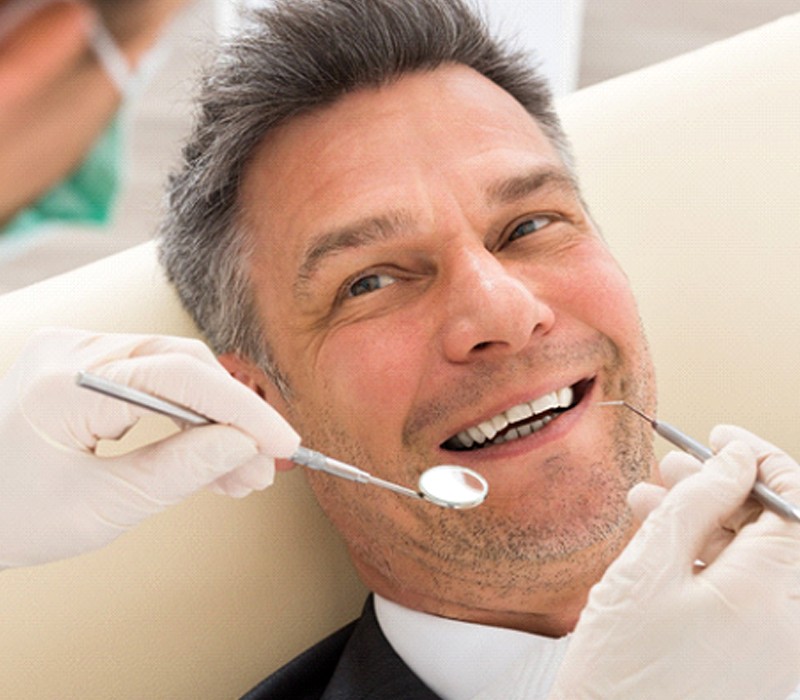 An older man smiling as his dentist in Flint prepares to examine his smile for potential cavities