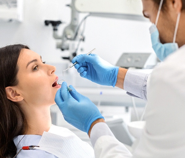 A female patient opens her mouth to let her dentist check her restoration to ensure it is in optimal shape in Flint