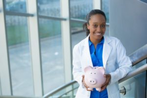 female dentist holding pink glass piggy bank 