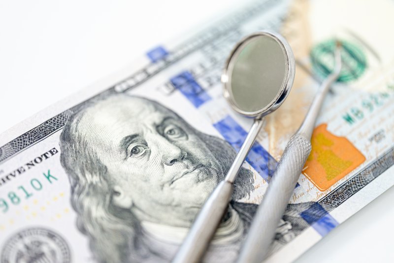 a hundred dollar bill next to dental tools