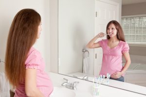 pregnant woman brushing teeth